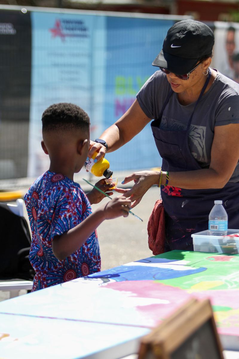 Community members painting at an outdoor table during the Out of Hand Theater NEXT BLVD engagement